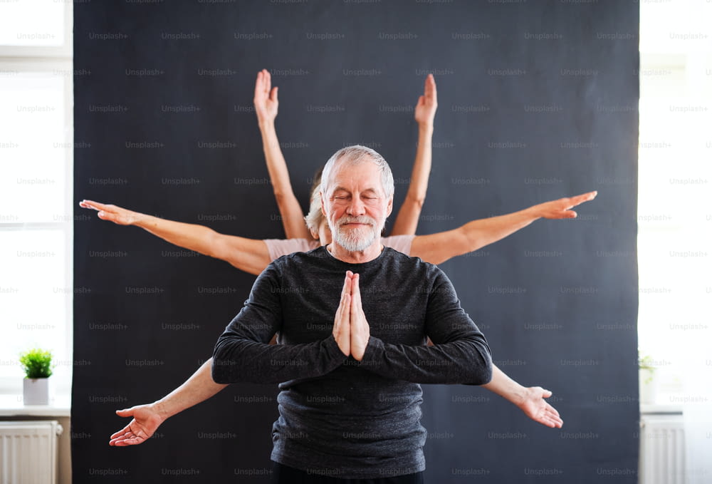 Un homme âgé aux bras multiples faisant des exercices de yoga dans un club de centre communautaire.