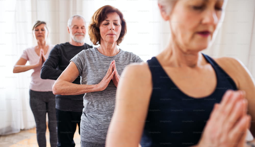 Groupe de personnes âgées actives faisant des exercices de yoga dans un club de centre communautaire.
