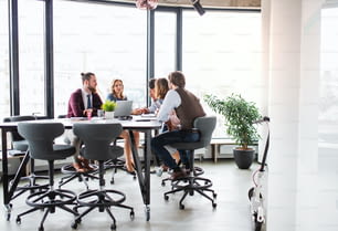 Un grupo de jóvenes empresarios sentados en una oficina, teniendo una reunión.