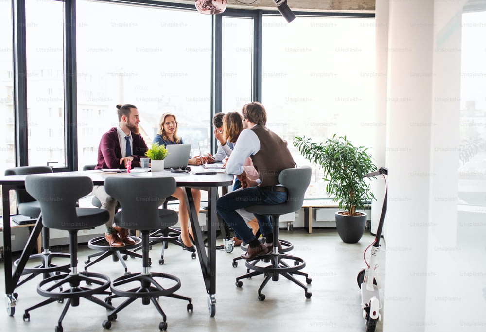 Um grupo de jovens empresários sentados em um escritório, tendo reunião.