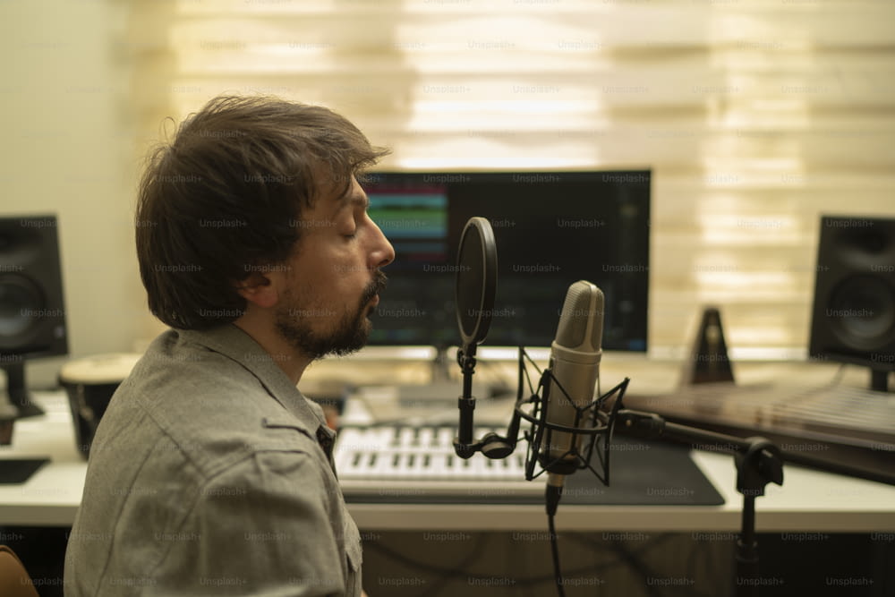 Un homme assis devant un micro dans un studio d’enregistrement