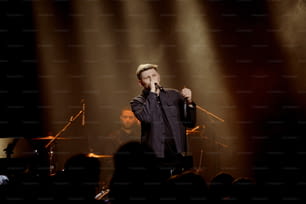 Un uomo in piedi su un palco con in mano un microfono