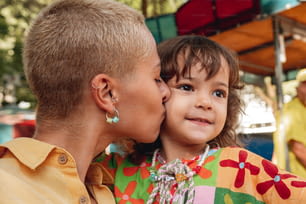 a woman kissing a little girl on the cheek