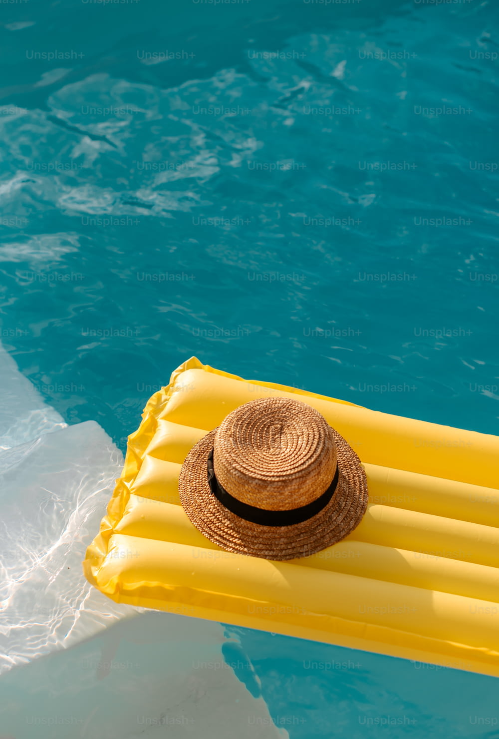 un cappello di paglia su una zattera che galleggia in una piscina