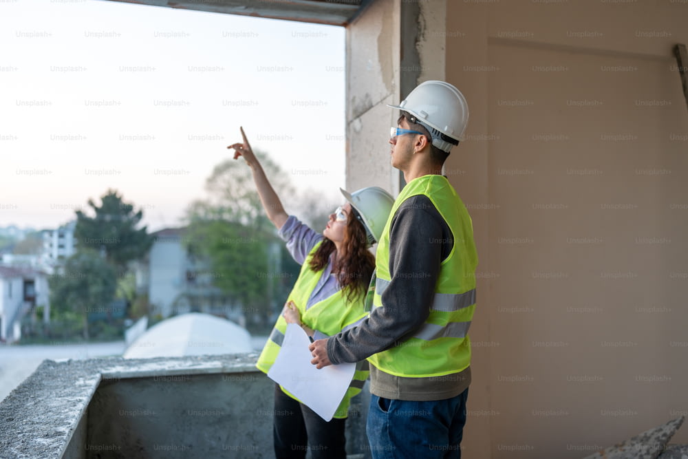 a man and a woman in safety vests pointing at something