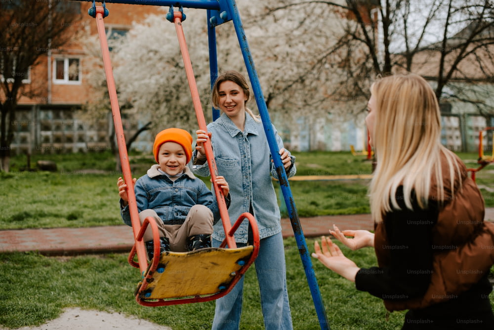 a woman talking to a child on a swing