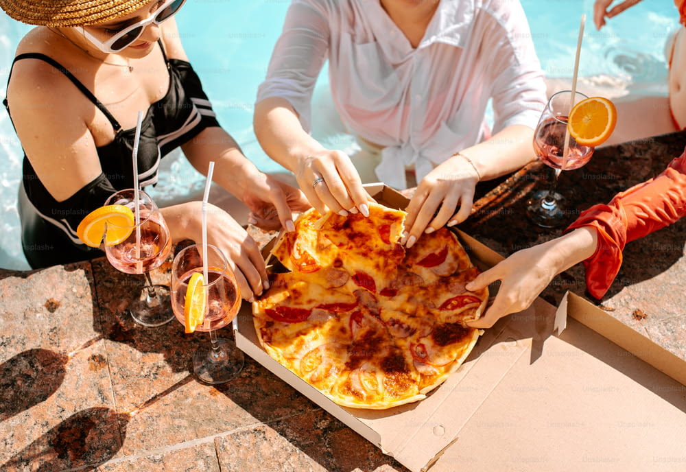 a group of people sitting around a table with pizza