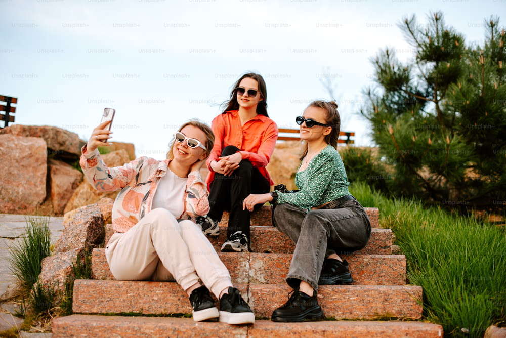 three women sitting on steps taking a selfie
