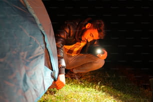 夜にテントの横にひざまずく男