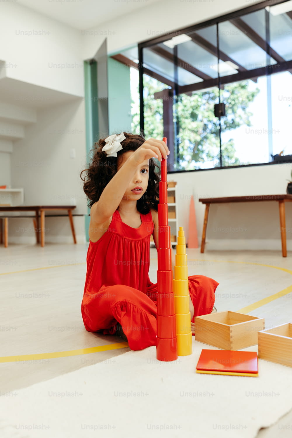 a little girl sitting on the floor playing with a building set