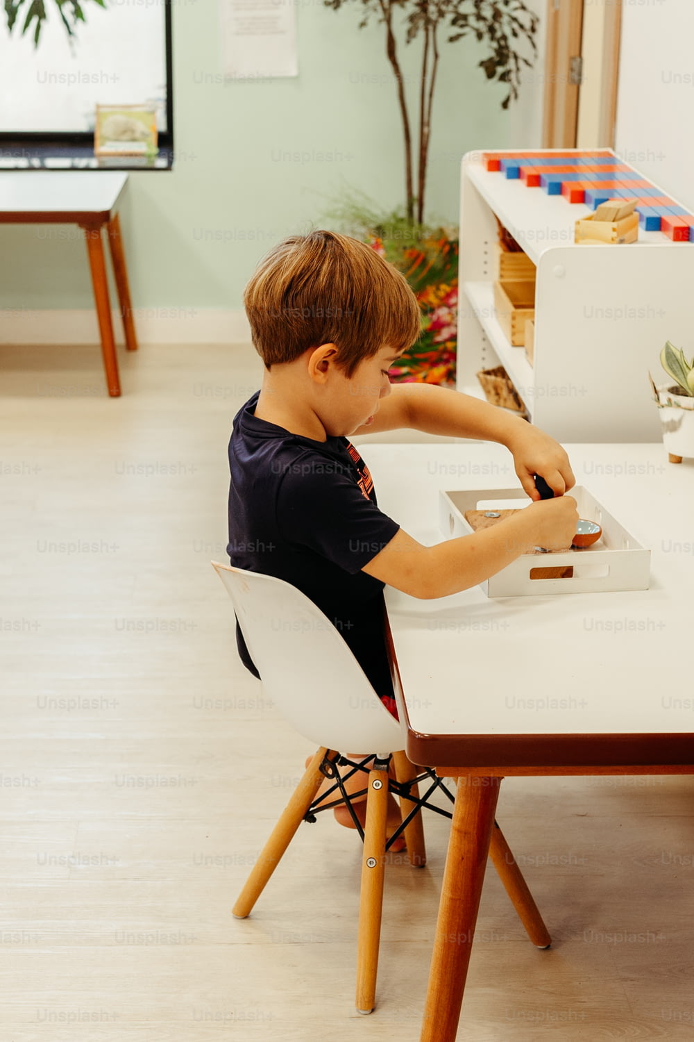 하얀 의�자가 있는 하얀 탁자에 앉아 있는 어린 소년