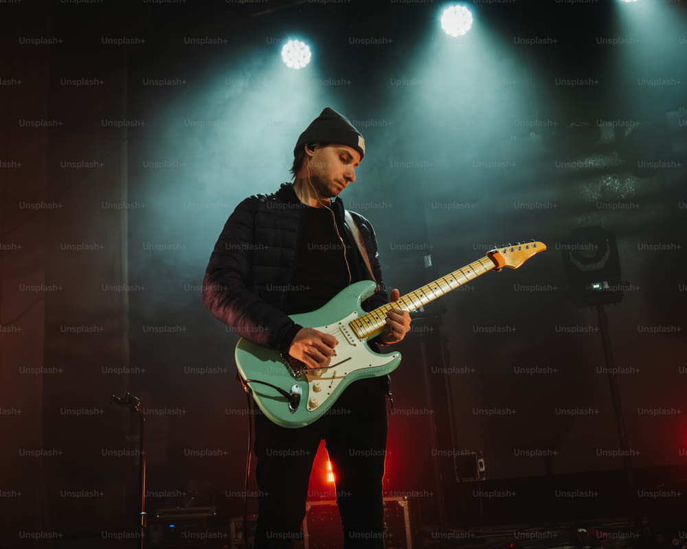 Un hombre tocando una guitarra en un escenario