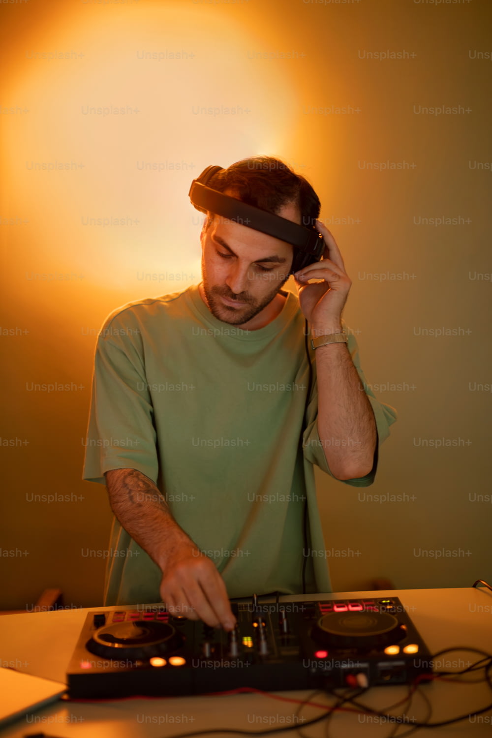 Un homme en chemise verte utilise la platine d’un DJ