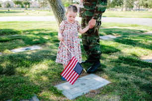 Une petite fille debout à côté d’un soldat tenant un drapeau américain