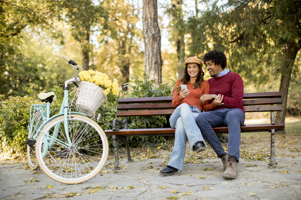 Multiratial loving couple sitting on bench in the autumn city park