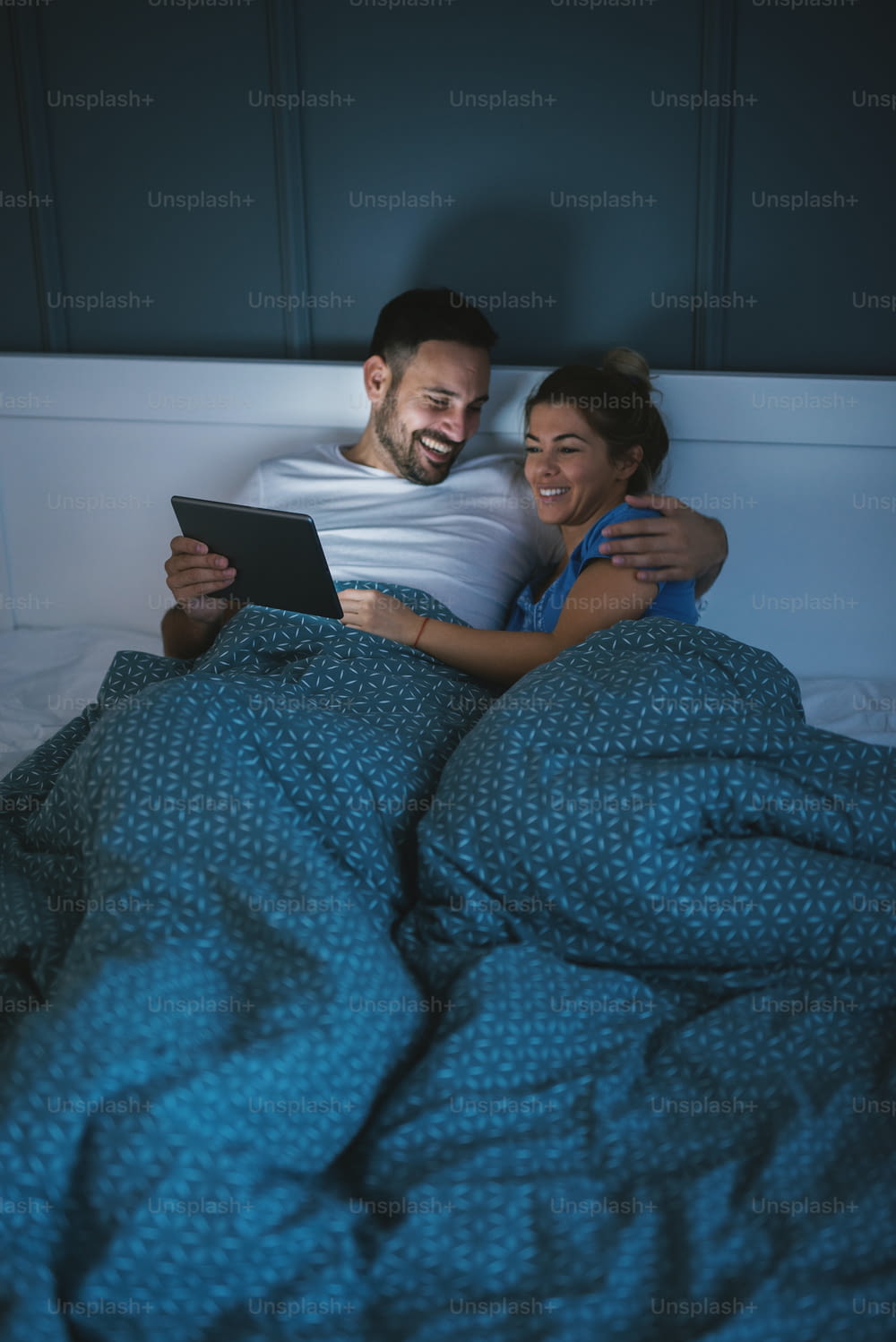 Feliz pareja relajada y satisfecha acostada en la cama y navegando por Internet.