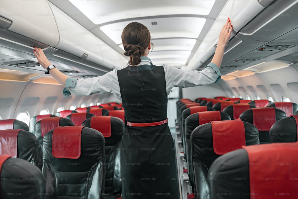 Female flight attendant doing her job in airplane stock photo. Airways concept