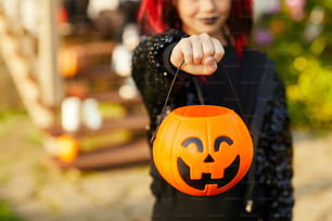Closeup of unrecognizable little girl wearing Halloween costume and holding pumpkin basket in trick or treat season, copy space