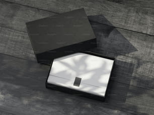야외에서 나무 테이블에 흰색 포장지가 있는 검은색 선물 상자 모형을 열었습니다. 3D 렌더링