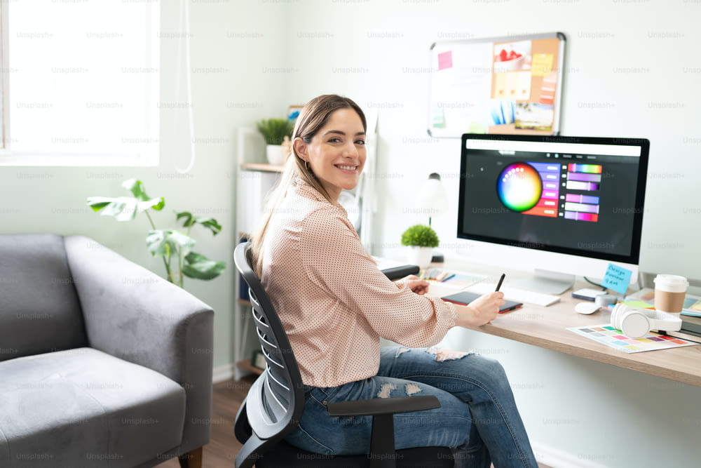 Mujer atractiva que trabaja como diseñadora gráfica con una tableta gráfica y elige los colores adecuados