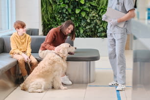 家族が犬と一緒に獣医クリニックに来て、獣医に見せる