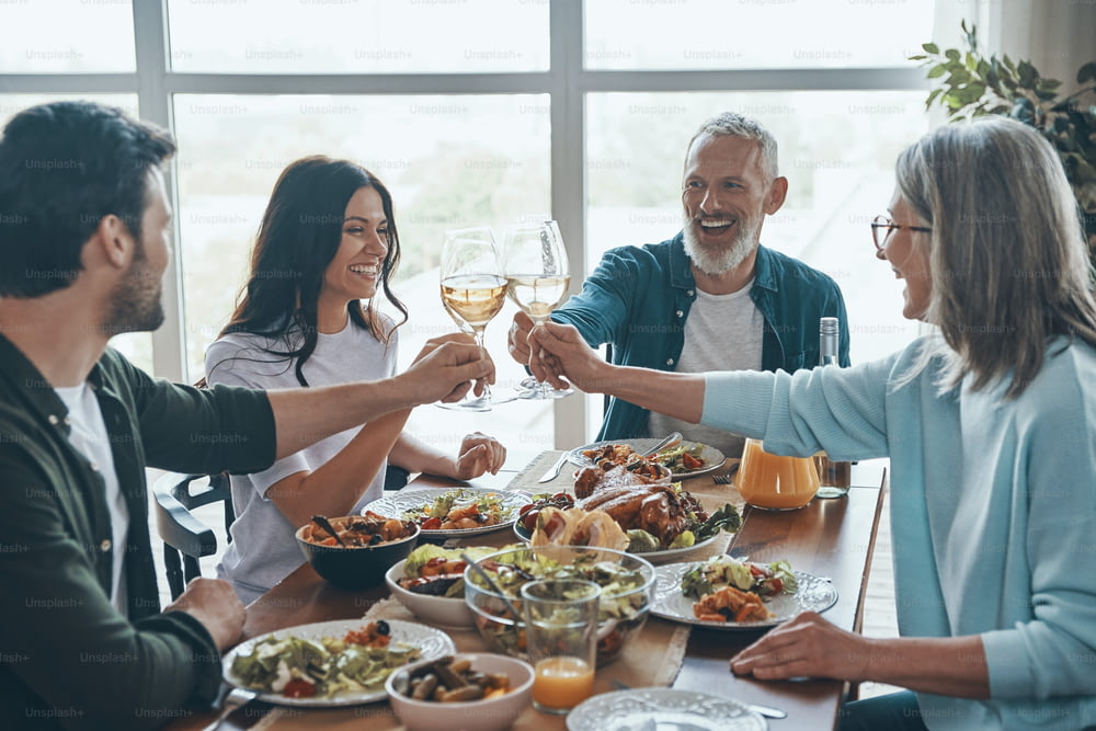 Happy multi-generation family toasting each other and smiling while having dinner together