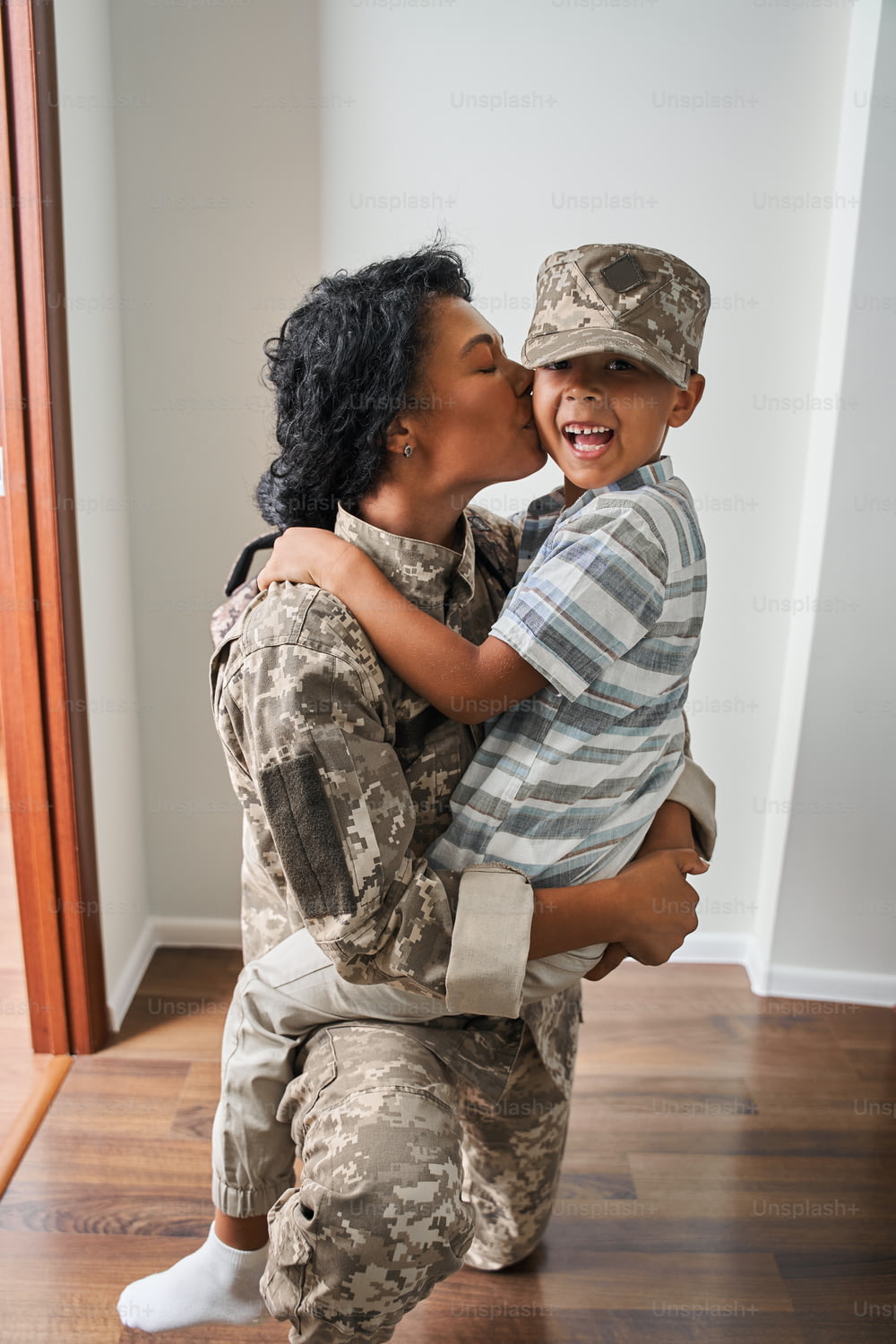 幸せな家族。うれしそうに喜ぶ軍の母親と彼女の息子はお互いを見て、楽しみながら微笑んでいます。再会後に息子にキスをする女性