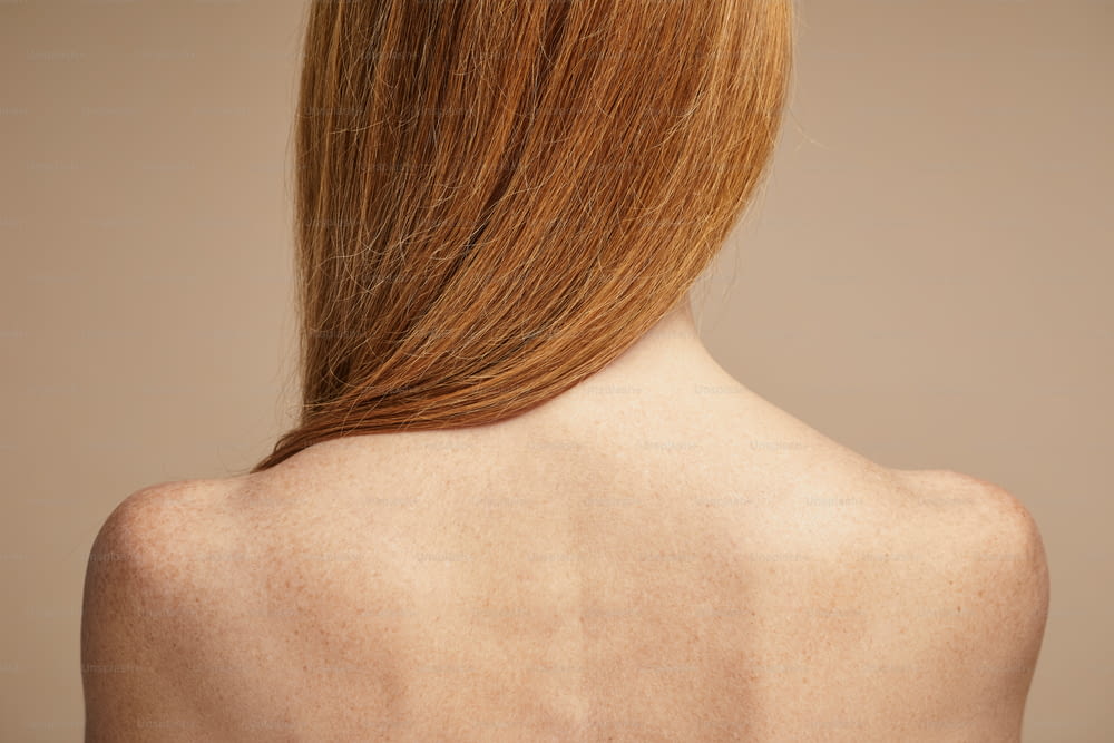 Minimale Rückansicht der sommersprossigen rothaarigen Frau mit nackten Schultern, Kopierraum