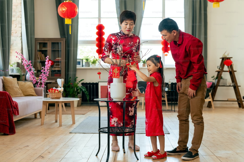 Familie von drei Dekorationsfilialen mit Postkarten mit den besten Wünschen für den Urlaub während der Vorbereitung auf das chinesische Neujahr