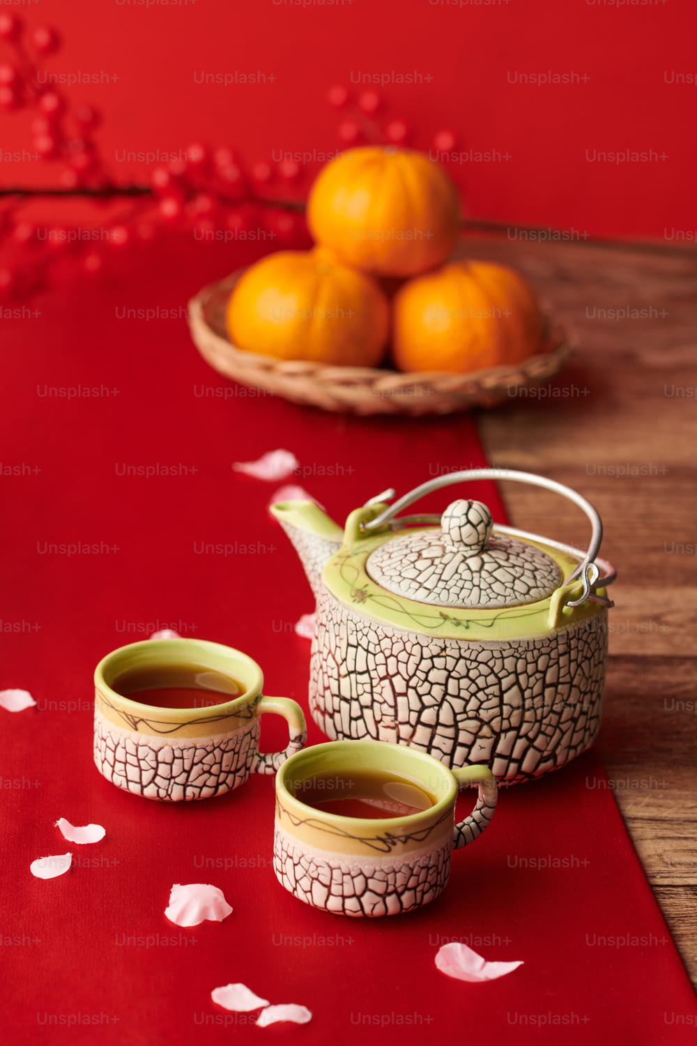 Pot and two cups of tea on table covered with red cloth traditional for Lunar New Year celebration