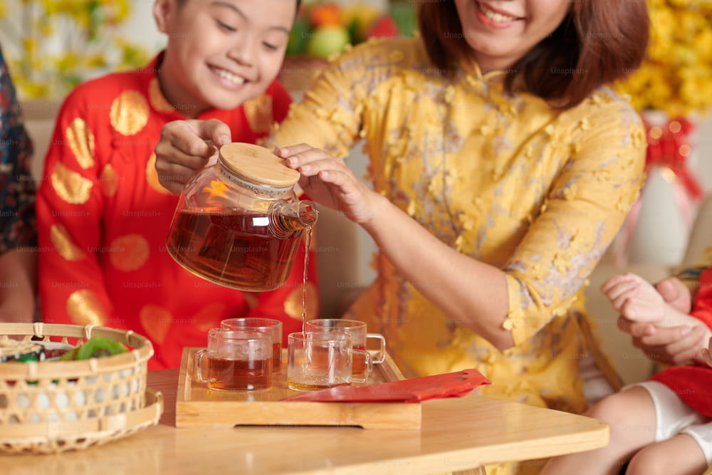Mutter schenkt ihrem Sohn beim chinesischen Neujahrsfest Tee ein