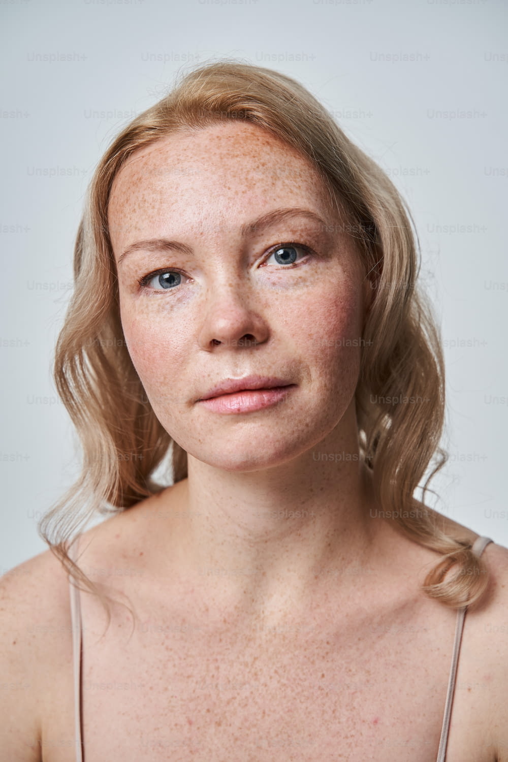 Young beautiful freckles woman face portrait with healthy skin. Vertical portrait view of the dreamy lady with perfect skin. Female appearance and cosmetology concept. Stock photo