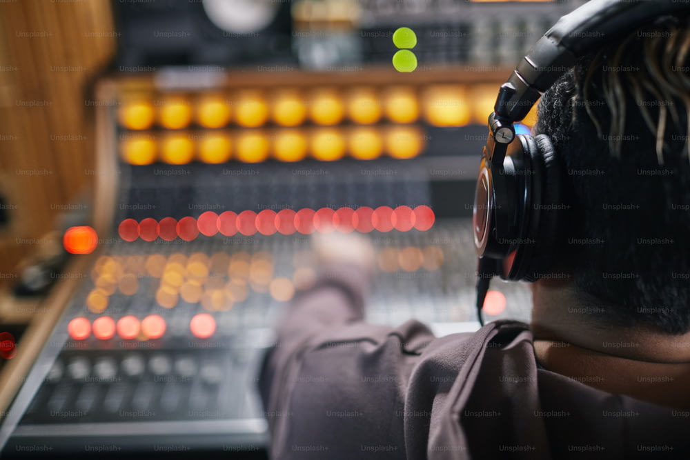 전문 녹음 스튜디오의 오디오 워크스테이션에서 헤드폰을 끼고 있는 젊은 음악가의 뒷모습, 복사 공간