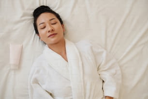 Une jeune femme s’est endormie sur son lit après avoir pris un bain chaud et appliqué du lotio