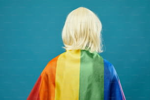 Vista traseira da bandeira do arco-íris da pessoa contra o fundo azul vibrante orgulho LGBTQ