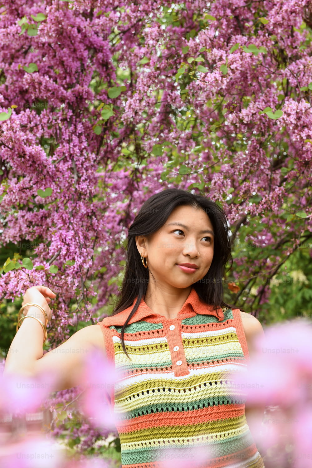 uma mulher em pé na frente de uma árvore com flores roxas