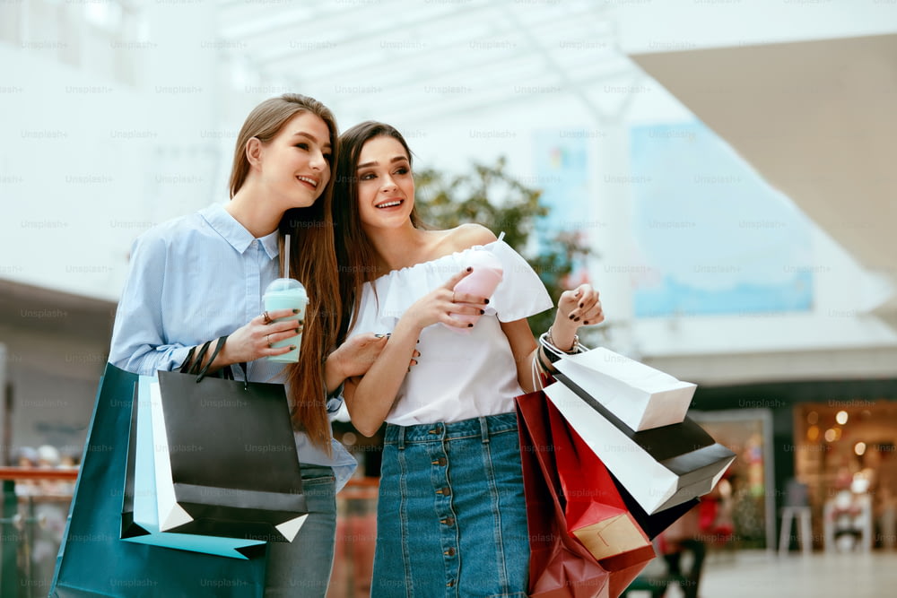 Mädchen beim Einkaufen. Schöne glückliche weibliche Freunde mit bunten Taschen in der Mall. Hohe Auflösung.