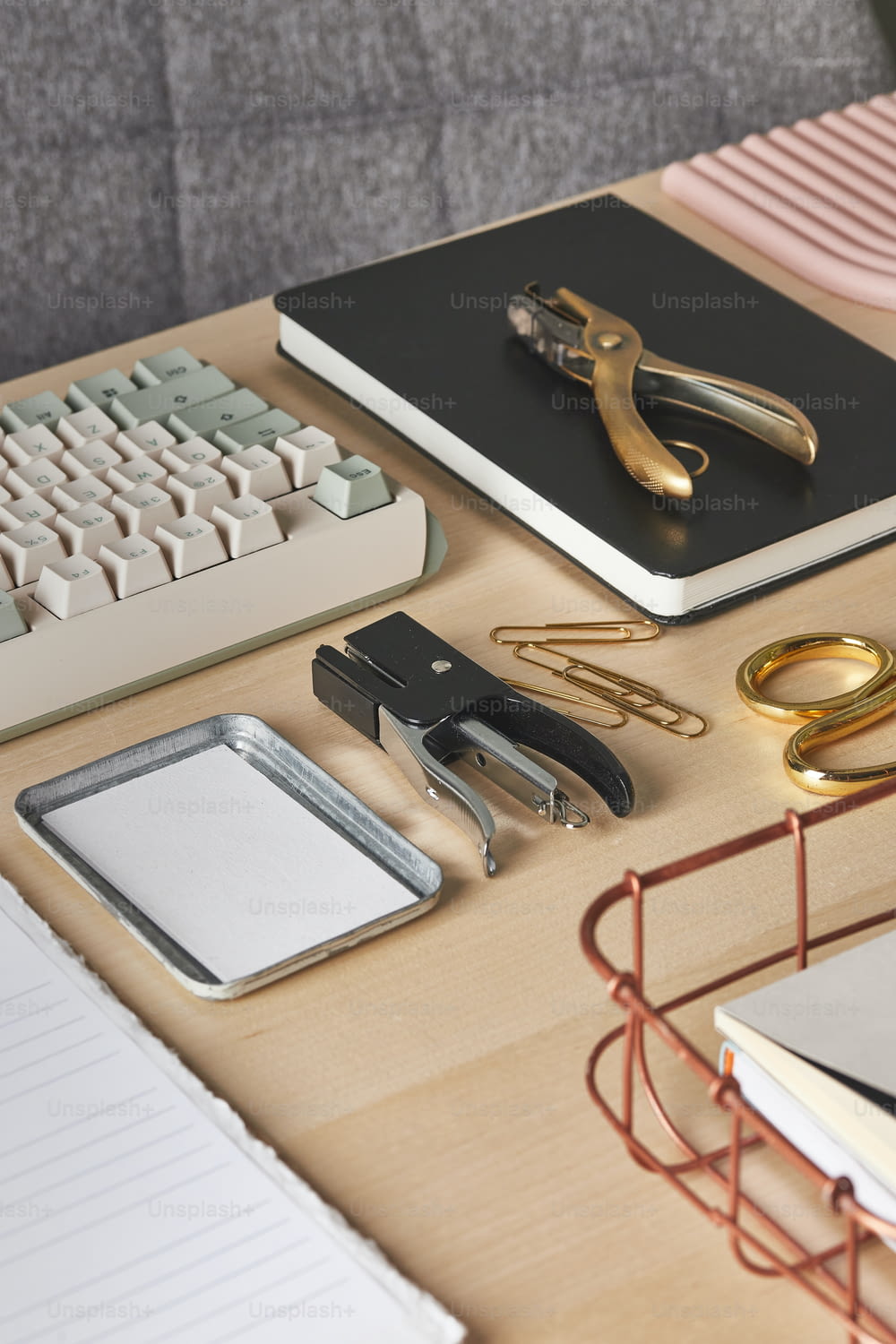 uma mesa com teclado, fichário, tesoura e outros materiais de escritório