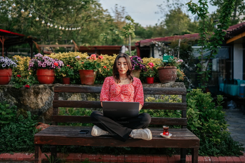a woman sitting on a bench with a laptop