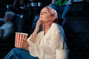 a woman with pink hair sitting in a theater