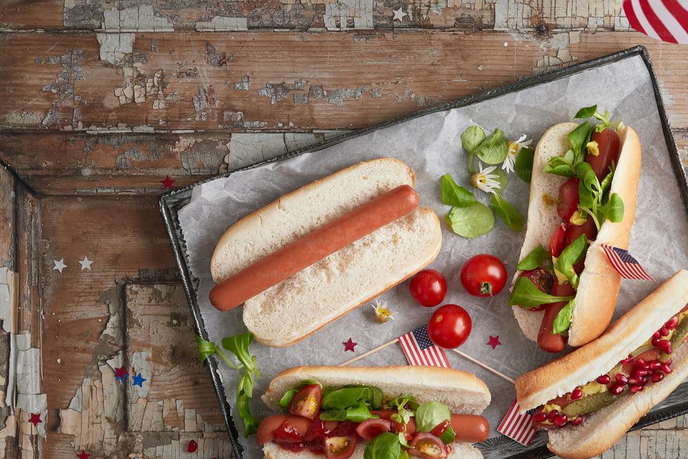 two hotdogs with tomatoes, lettuce and tomatoes on a tray