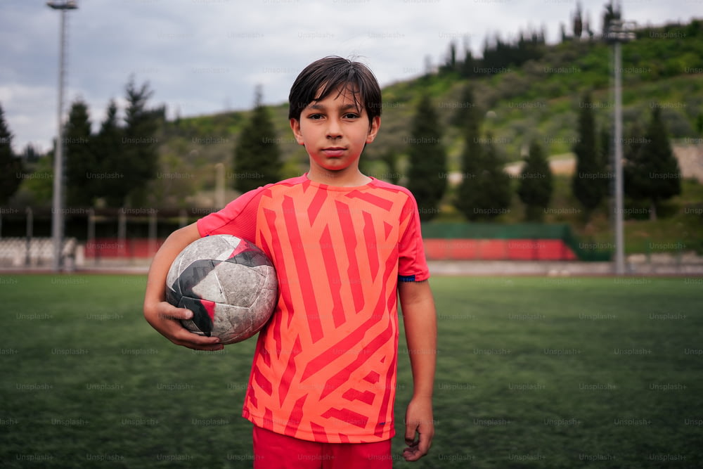 a young boy holding a soccer ball on a field