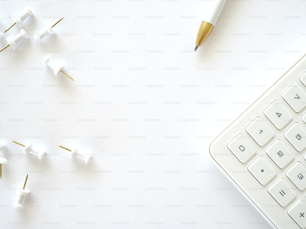 un teclado y un bolígrafo sobre una superficie blanca
