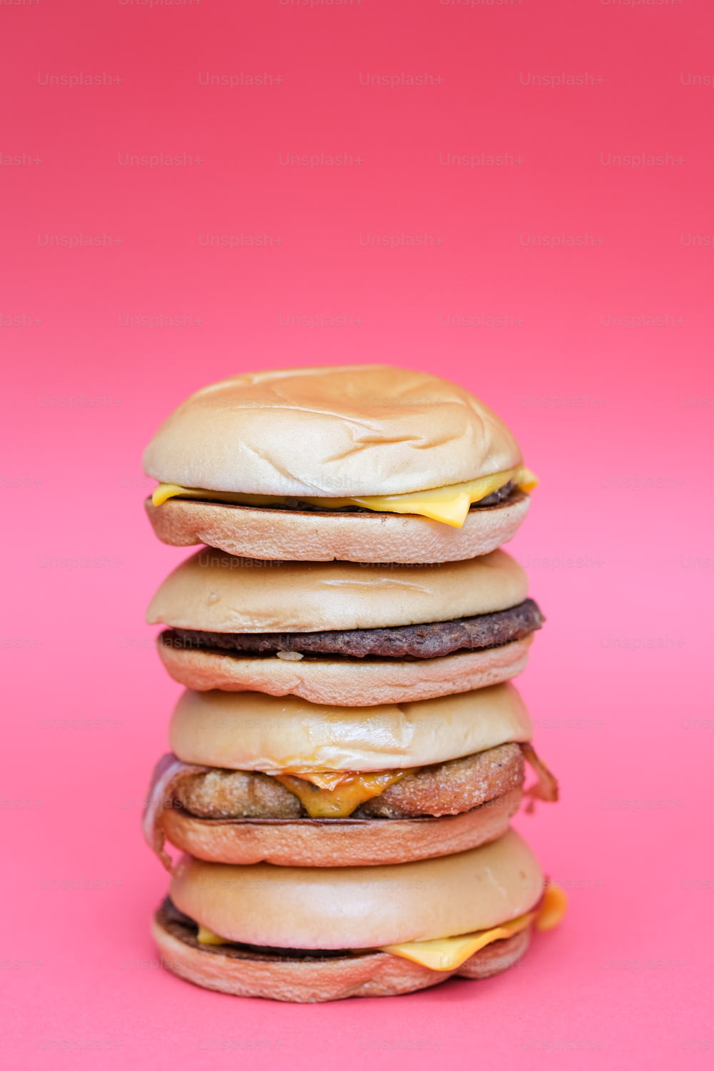 a stack of hamburgers on a pink background