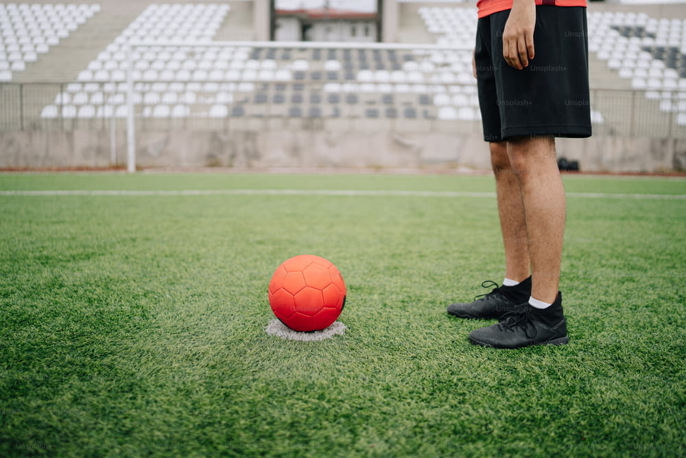 Un uomo in piedi accanto a un pallone da calcio su un campo
