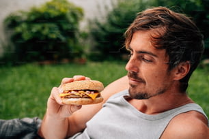 a man sitting in the grass eating a sandwich