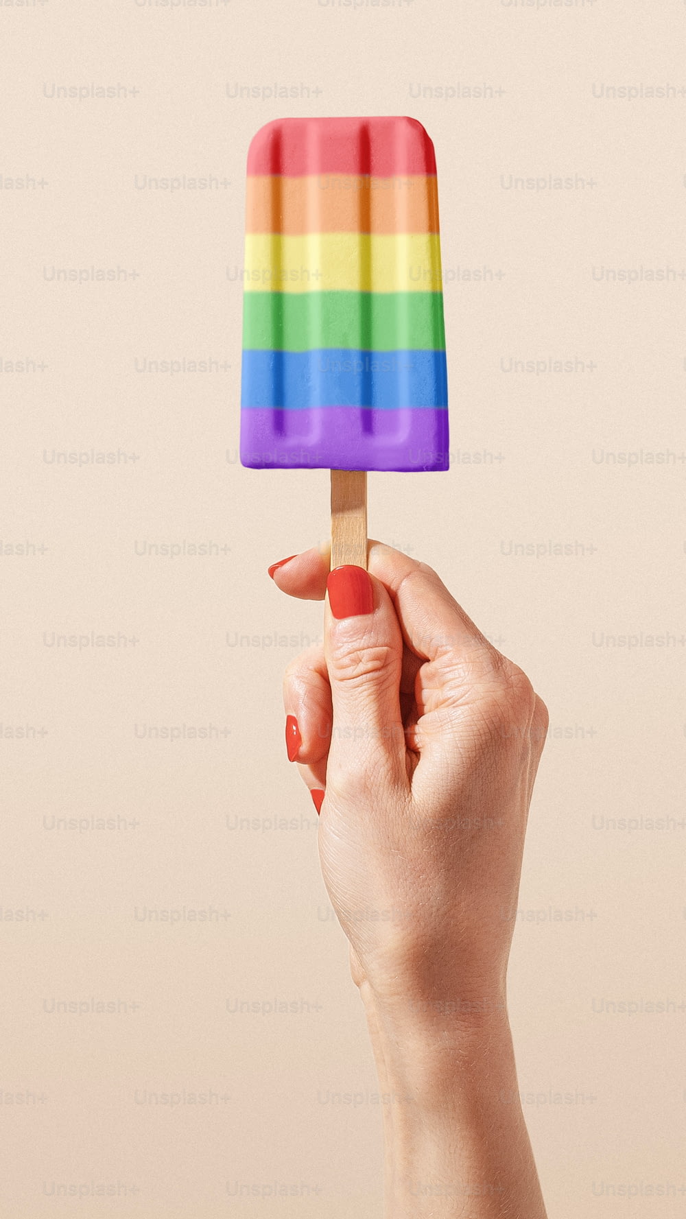 虹のついたアイスキャンディーを持つ手