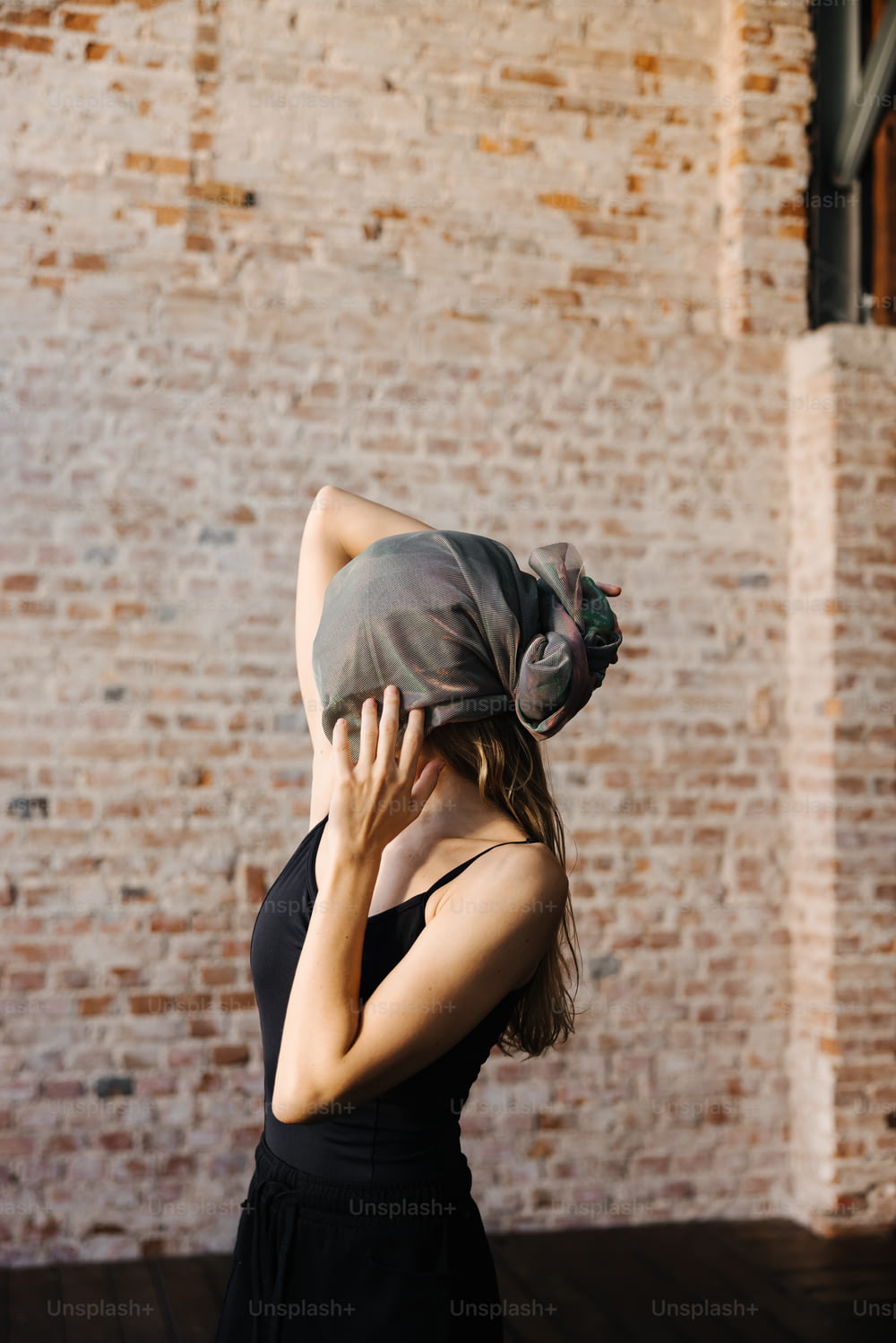 a woman in a black dress is covering her face with a scarf