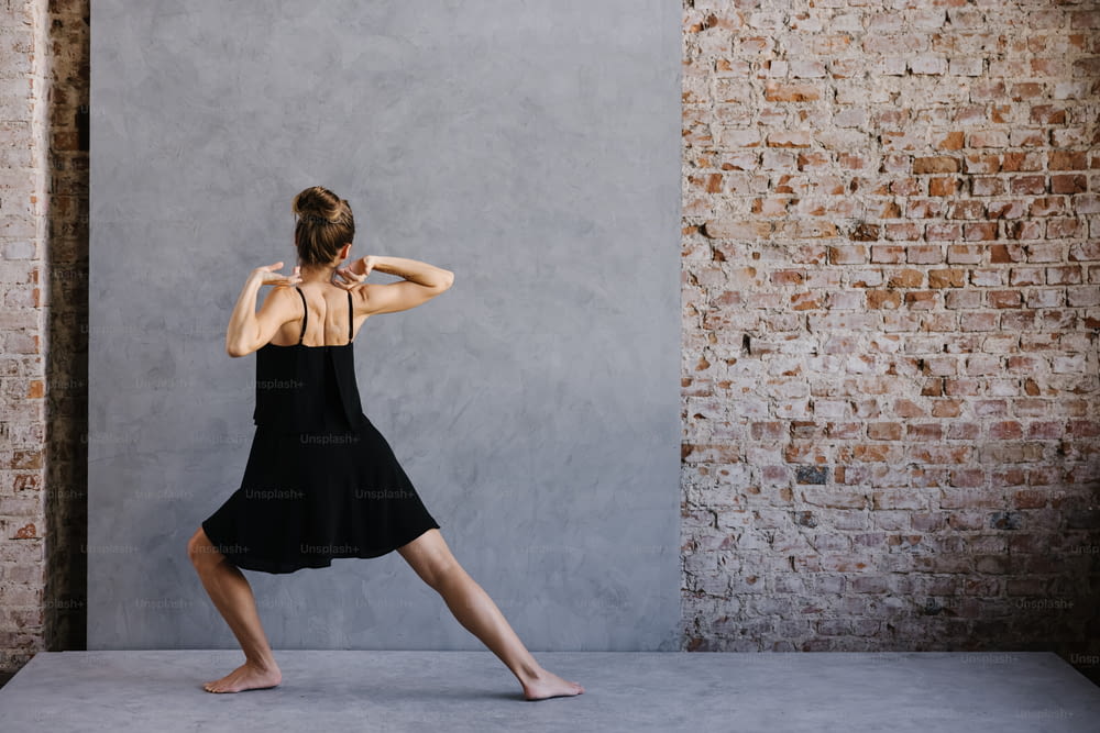 uma mulher em um vestido preto está fazendo uma pose de ioga