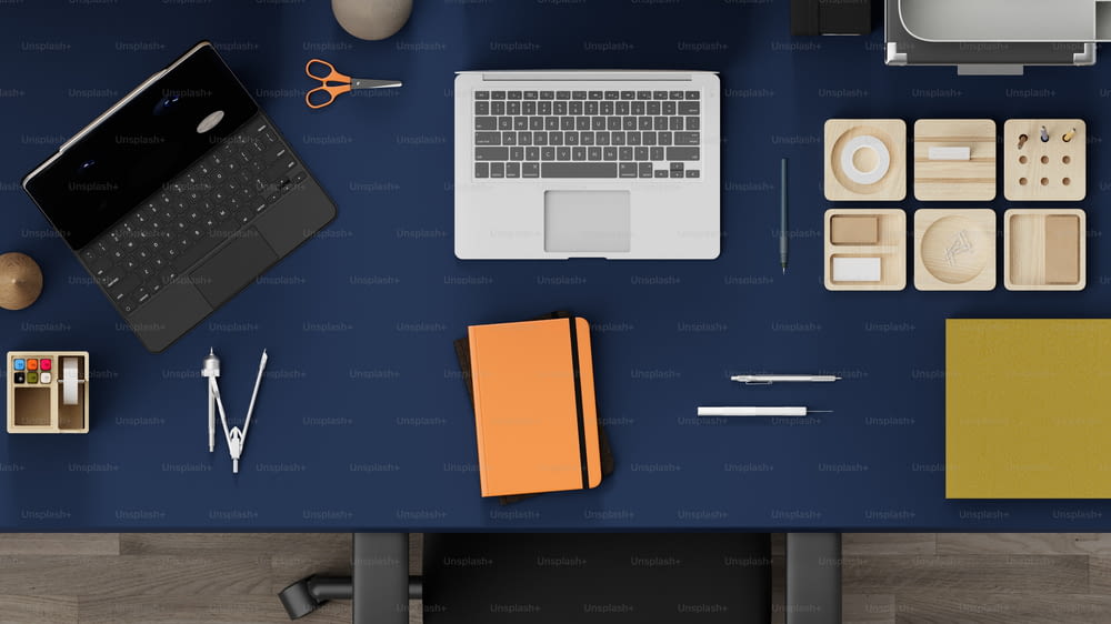 uma mesa com laptop, notebook e outros materiais de escritório